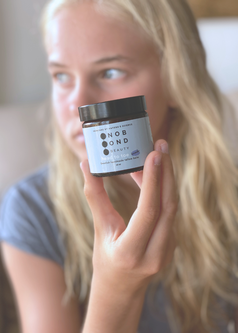Kvinna håller No Bond Beauty Tallow Face Balm – naturlig hudvård med svenskt talg för mjuk och återfuktad hud